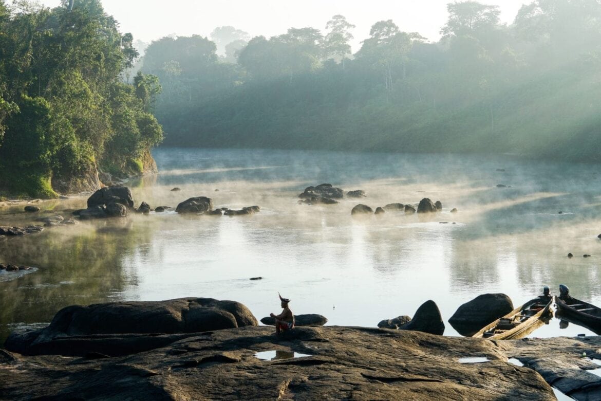 Indigenous man sitting along the banks river bank in the Amazon rainforests of Suriname.